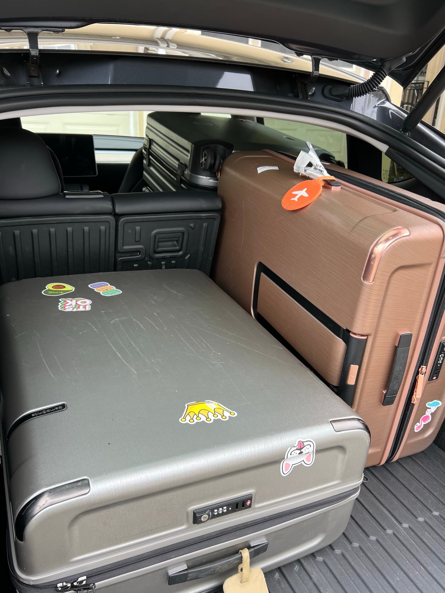 Several large hard-shell suitcases packed tightly into the rear of a Model Y